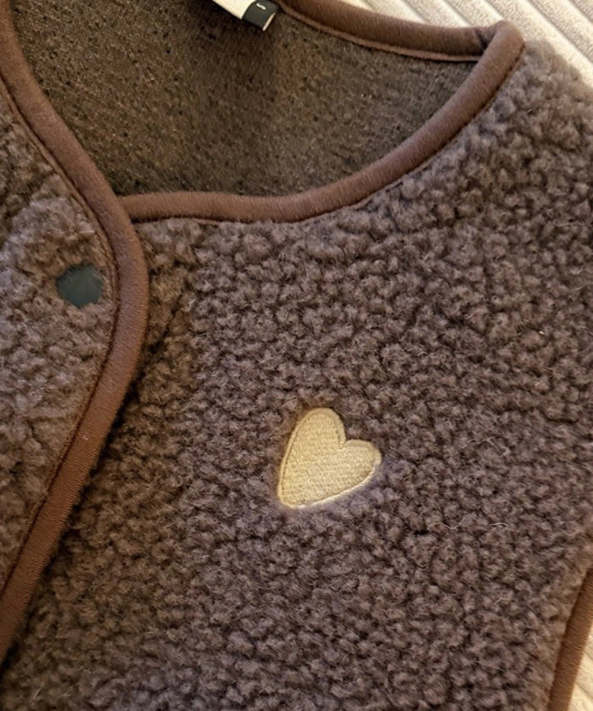 Dunkelbraune TYB Wollweste mit cremefarbenem Herz, Detail